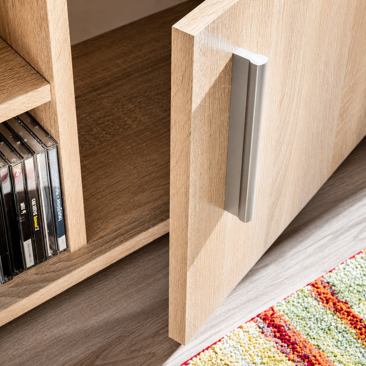 Détail de la porte en bois chêne sonoma avec poignée moderne sur le meuble TV Loftora