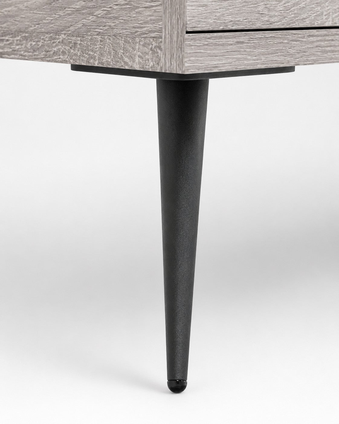 Pied conique en métal noir du meuble TV Loftora en finition bois gris Sonoma